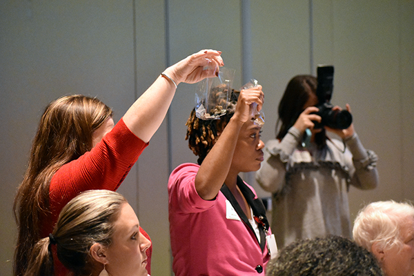 Participants hold up their bags of rocks at the end of the exercise to illustrate how environmental stresses and poverty weigh us down on our walk through life.