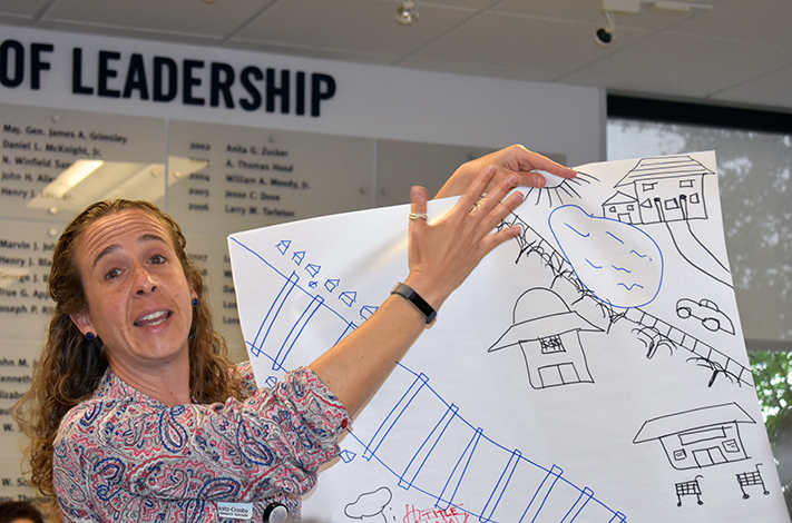 Attendees of Healthy Tri-County's Conversation on Race and Health Equity broke into groups and drew representations of social determinants and equity. Christina Holtz-Crosby of PASOs shares her groups drawing.